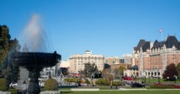 a fountain in the middle of a park with buildings in the background