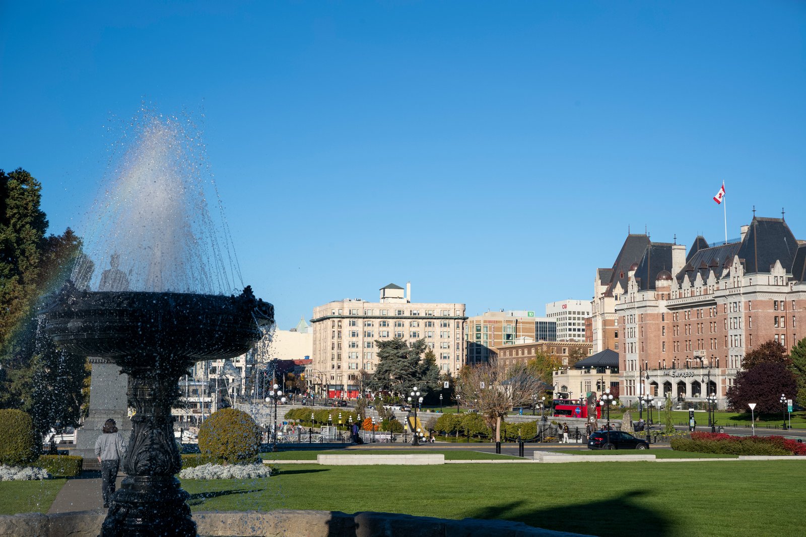 a fountain in the middle of a park with buildings in the background